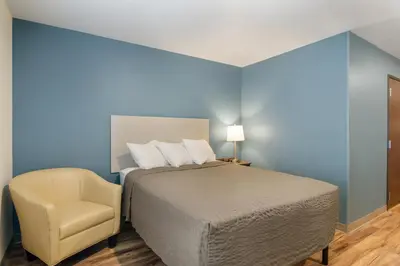 a bedroom with a bed and a chair at WoodSpring Suites Thornton-North Denver in Thornton