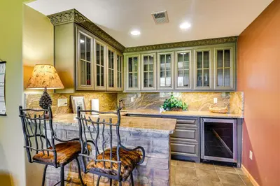 a kitchen with a counter with chairs and cabinets at 1 Mi to Grand Lake Family-Friendly Gem with Hot Tub in Grand Lake