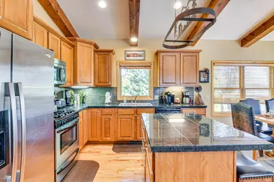 a kitchen with wooden cabinets and a stainless steel refrigerator at 1 Mi to Grand Lake Family-Friendly Gem with Hot Tub in Grand Lake