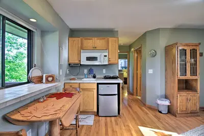 a kitchen with wooden cabinets and a table in it at Loveland Guest House with Balcony by Boyd Lake in Loveland