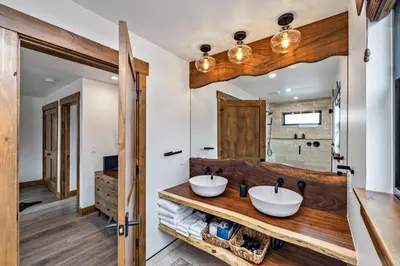 a bathroom with two sinks and a large mirror at Slice of Heaven just steps from Lake Estes! Indoor/Outdoor Fireplace and Jacuzzi in Estes Park