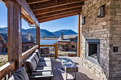 a porch with a fireplace on a log house at Slice of Heaven just steps from Lake Estes! Indoor/Outdoor Fireplace and Jacuzzi in Estes Park
