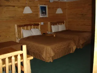 two beds in a room with wooden walls at Georgetown Mountain Inn in Georgetown