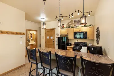 a kitchen with a bar with chairs and a counter top at 8115 Arapahoe Lodge condo in Keystone