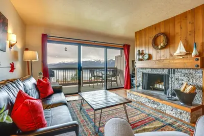 a living room with a fireplace and a view of the mountains at 8 Mi to Keystone Resort Dillion Condo with Hot Tub! in Dillon