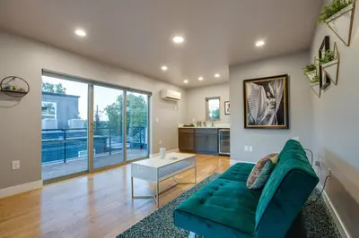a living room with a green couch and a table at Heated Rooftop Deck and Mtn Views Denver Retreat in Englewood