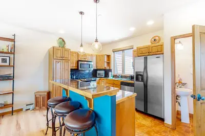 a kitchen with wooden cabinets and a blue island with bar stools at WinterStar E-2 in Fraser