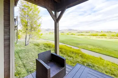 a chair on a porch with a view of a golf course at Mountain Sky in Granby