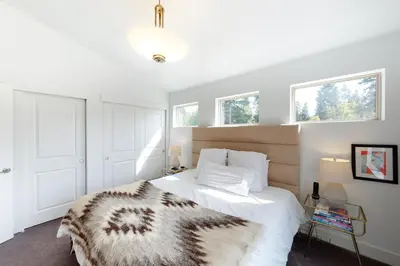 a bedroom with a bed and two windows at Mountain Sky Cottage in Fraser