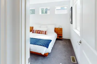 a small bedroom with a bed and two windows at Mountain Sky Cottage in Fraser