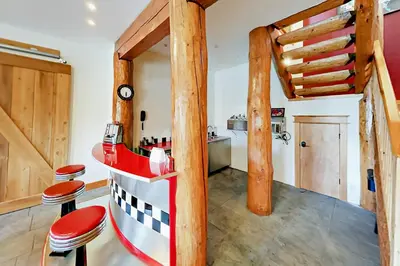 a kitchen with wooden beams and stools in a room at Hilltop Palace in Fraser