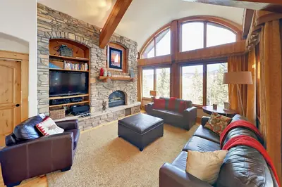 a living room with a couch and a stone fireplace at Hilltop Palace in Fraser