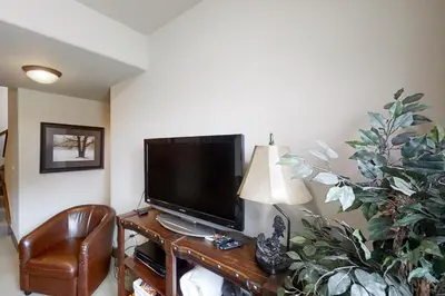 a living room with a flat screen tv and a chair at Deer Track Retreat in Granby