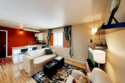 a living room with a couch and a kitchen at Winter Park Meadows Lodge in Fraser