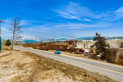 a car driving down a road with mountains in the background at Winter Park Meadows Lodge in Fraser