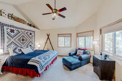 a bedroom with a bed and a chair and a ceiling fan at Hemlock Cabin in Granby