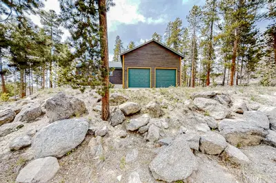 a house in the woods with rocks in front of it at Hemlock Cabin in Granby