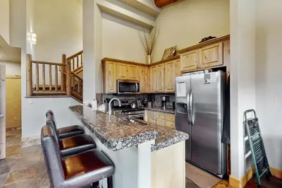 a kitchen with a stainless steel refrigerator and wooden cabinets at The Antlers 401 in Winter Park