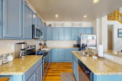 a blue kitchen with marble counter tops and blue cabinets at Sagebrush Cabin in Granby