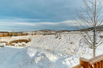 a snow covered field with a bench and a tree at Sagebrush Cabin in Granby