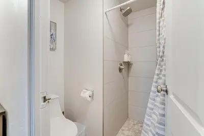 a white bathroom with a shower and a toilet at Walk to Main St! Condo with Hot Tub and Pool in Frisco in Frisco