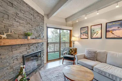 a living room with a fireplace and a stone wall at Walk to Main St! Condo with Hot Tub and Pool in Frisco in Frisco