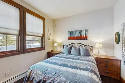 a bedroom with a bed and two windows at Bluebird Skies in Granby