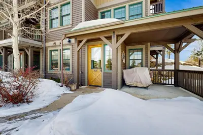 a house with a yellow door in the snow at Bluebird Skies in Granby