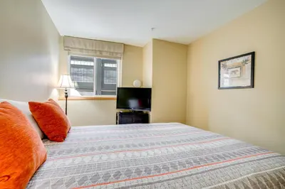 a bedroom with a bed with orange pillows and a television at Silverthorne Gem with Community Perks 11 Mi to Ski! in Silverthorne