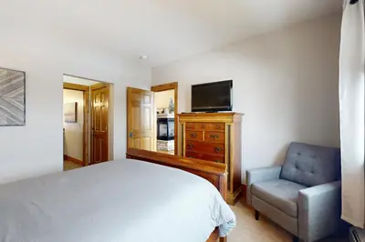 a bedroom with a bed and a chair and a television at Granby Grandeur in Granby