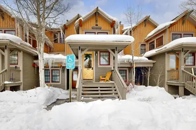 a snow covered house with a sign in front of it at Granby Grandeur in Granby
