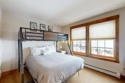a bedroom with a bunk bed and two windows at Granby Grandeur in Granby