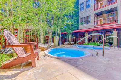 a patio with a hot tub and a chair and a building at Silvermill Lodge 8250 in Keystone