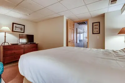 a bedroom with a large white bed and a television at Premiere 2Br Townhome - Shuttle to Slopes, Kids Ski Free! condo in Keystone