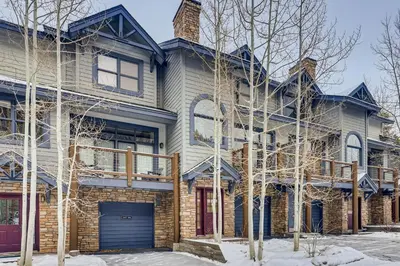 a brick house with a garage in the snow at Premiere 2Br Townhome - Shuttle to Slopes, Kids Ski Free! condo in Keystone