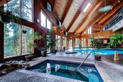 an indoor pool in a house with wooden ceilings and windows at Pool, Hot Tub and Ski Shuttle! Silverthorne Condo in Silverthorne