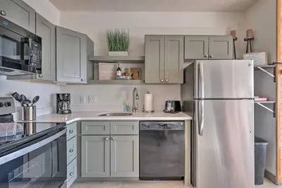 a kitchen with white cabinets and a stainless steel refrigerator at Pool, Hot Tub and Ski Shuttle! Silverthorne Condo in Silverthorne