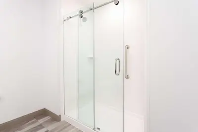 a glass shower in a bathroom with white walls at Hilton Garden Inn Broomfield Boulder in Broomfield