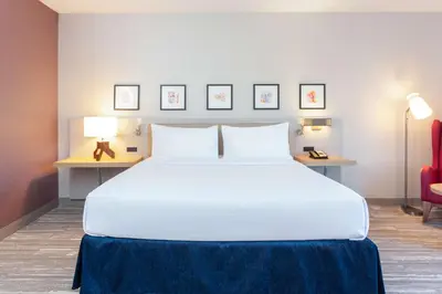 a bedroom with a large white bed and a red chair at Hilton Garden Inn Broomfield Boulder in Broomfield