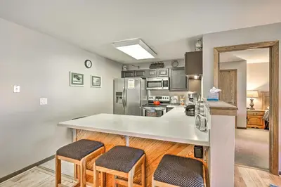 a kitchen with a white counter and stools in it at Condo with Balcony and Fireplace in Silverthorne! in Silverthorne