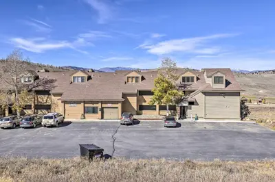 a large house with cars parked in a parking lot at Ski-InandOut Granby Condo with Mtn Views and Balcony! in Granby