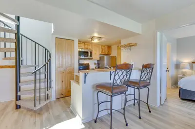 a kitchen and living room with two chairs at a counter at Ski-InandOut Granby Condo with Mtn Views and Balcony! in Granby