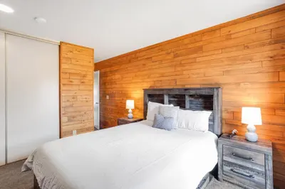 a bedroom with a white bed and wooden walls at Mountain Views & Meadows in Silverthorne