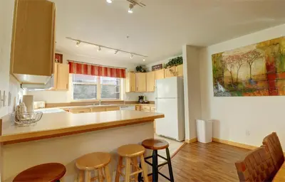 a kitchen with a white refrigerator and wooden stools at 101 Streamside Lane condo in Frisco