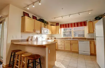 a kitchen with wooden cabinets and a island with bar stools at 101 Streamside Lane condo in Frisco