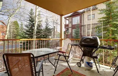 a grill on a patio with a table and chairs at 101 Streamside Lane condo in Frisco