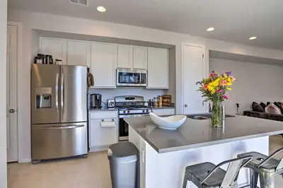 a kitchen with a stainless steel refrigerator and white cabinets at Near Hiking and Biking Trails Townhome with Patio in Aurora