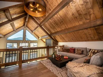a living room with a vaulted ceiling with wooden beams at Private end unit with Jacuzzi, Two Patios, and Indoor/Outdoor Fireplace in Estes Park