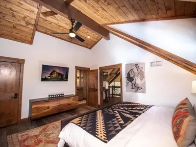 a bedroom with a large bed and wooden ceilings at Private end unit with Jacuzzi, Two Patios, and Indoor/Outdoor Fireplace in Estes Park