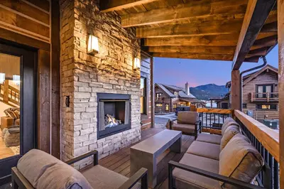 a living room with a stone fireplace on a balcony at Private end unit with Jacuzzi, Two Patios, and Indoor/Outdoor Fireplace in Estes Park